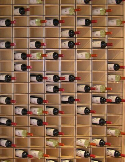 A wall-mounted wine rack filled with various bottles in a vertical and horizontal arrangement.