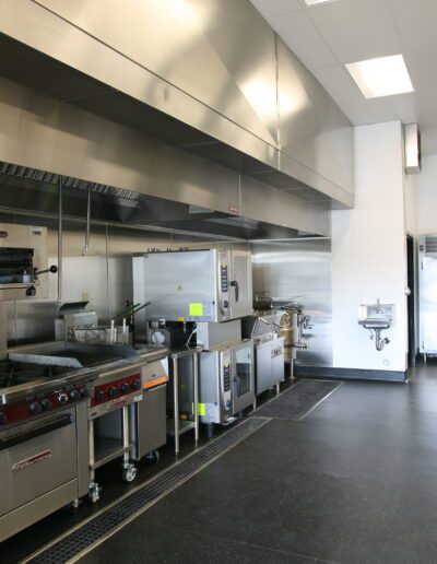 A clean and empty commercial kitchen with stainless steel appliances and work surfaces.