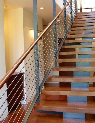 Modern staircase with wooden steps, glass balustrade, and brick wall interior.