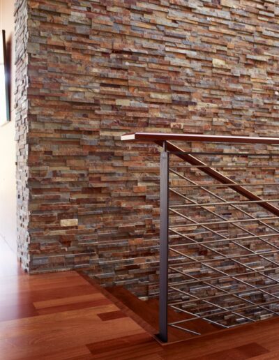 Modern interior with textured brick wall and sleek metal staircase railing.