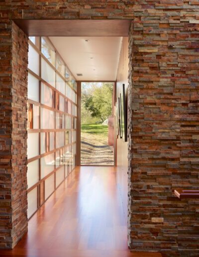 A modern hallway with exposed brick walls and floor-to-ceiling windows looking out to a garden.