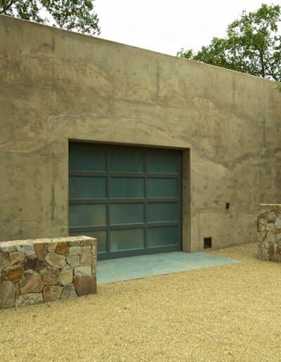 Modern concrete building with large blue door set against natural landscape.
