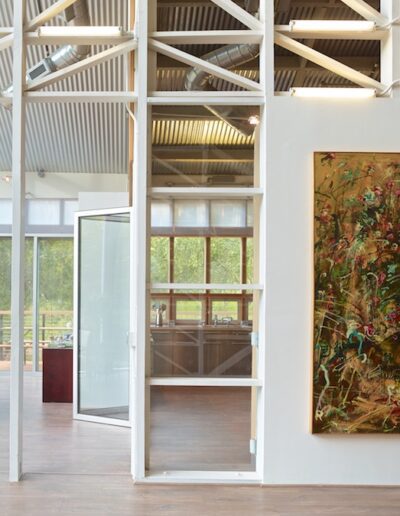Modern gallery interior with natural light, featuring a large abstract painting on the wall.