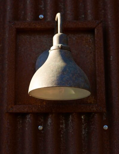 Vintage wall-mounted lamp on a rusted corrugated metal surface.