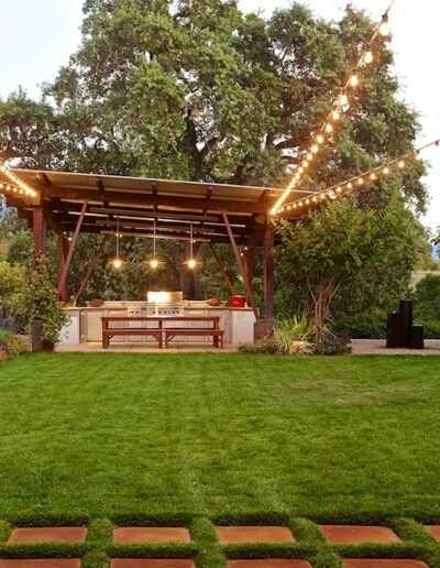 Outdoor patio with string lights, a dining area, and surrounding garden at dusk.