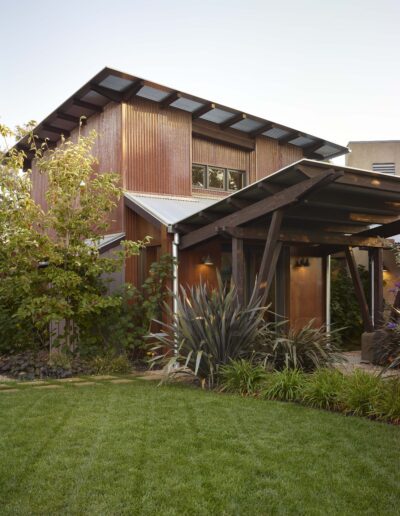 A modern house with wooden siding and a lush green lawn.