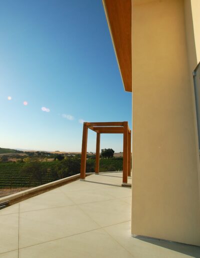 Modern terrace overlooking vineyard with clear blue sky.