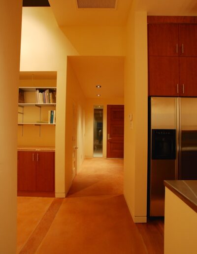 Modern kitchen hallway with wooden cabinetry and terracotta flooring.