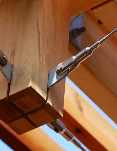 Wooden beam joint secured by metal turnbuckles and tension rods.