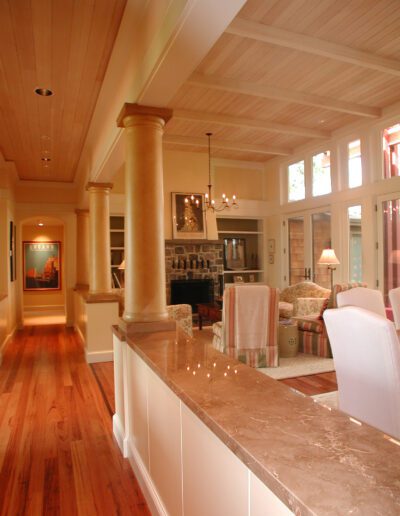Elegant home interior with a spacious kitchen featuring marble countertops, wooden floors, and classic column details.